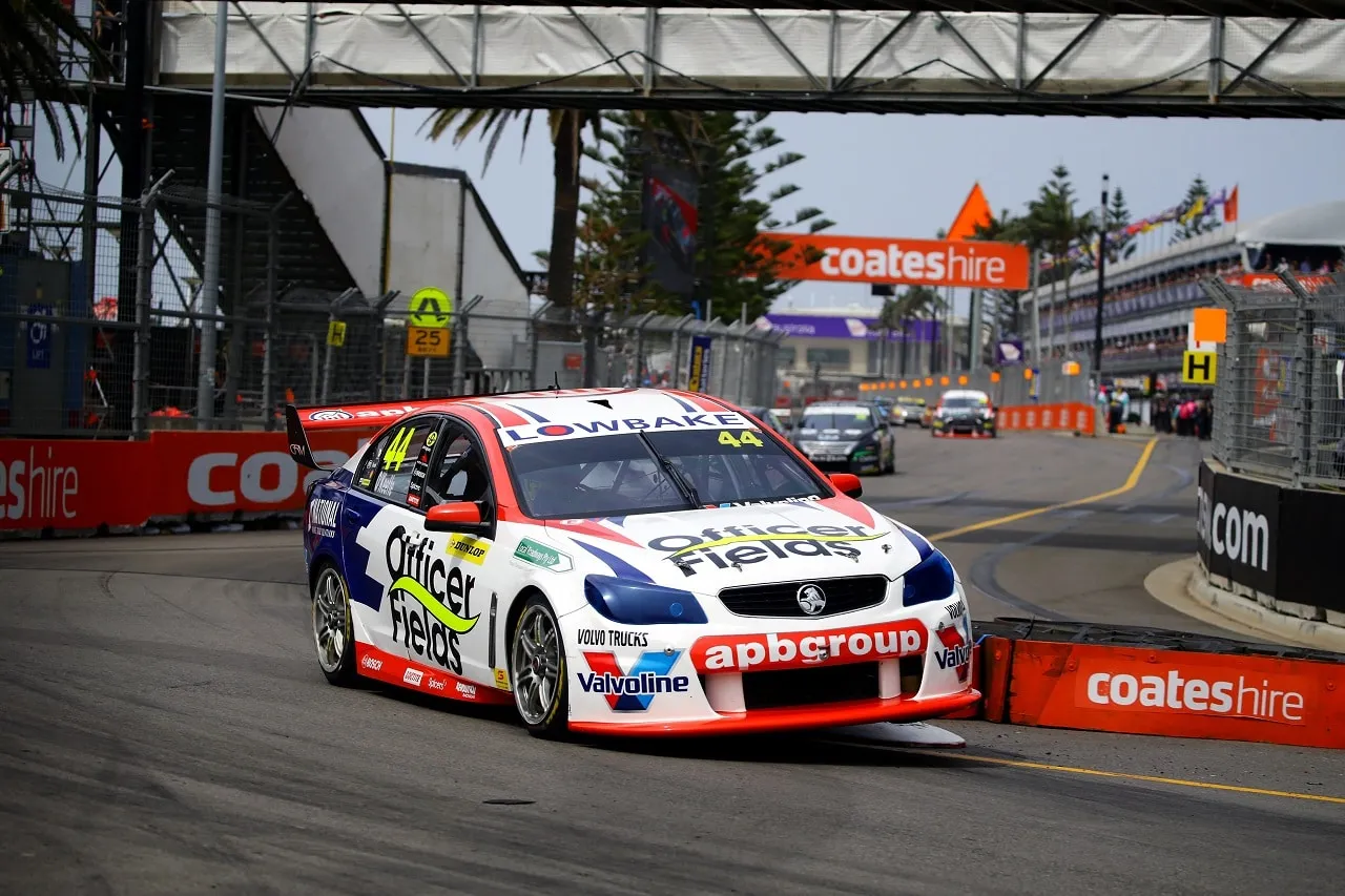 The #44 Officer Fields apbgroup Holden Commodore Supercar racing between Coates Hire barriers on the Newcastle street circuit