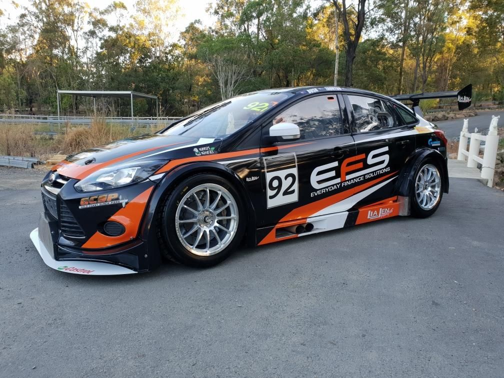The black and orange #92 Everyday Finance Solutions (EFS) MARC Ford Focus race car parked outdoors