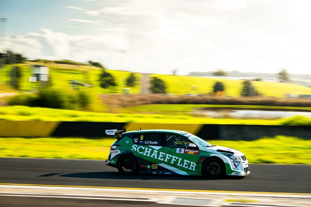 The #8 Schaeffler Peugeot 308 TCR car in side profile on track with green hills behind