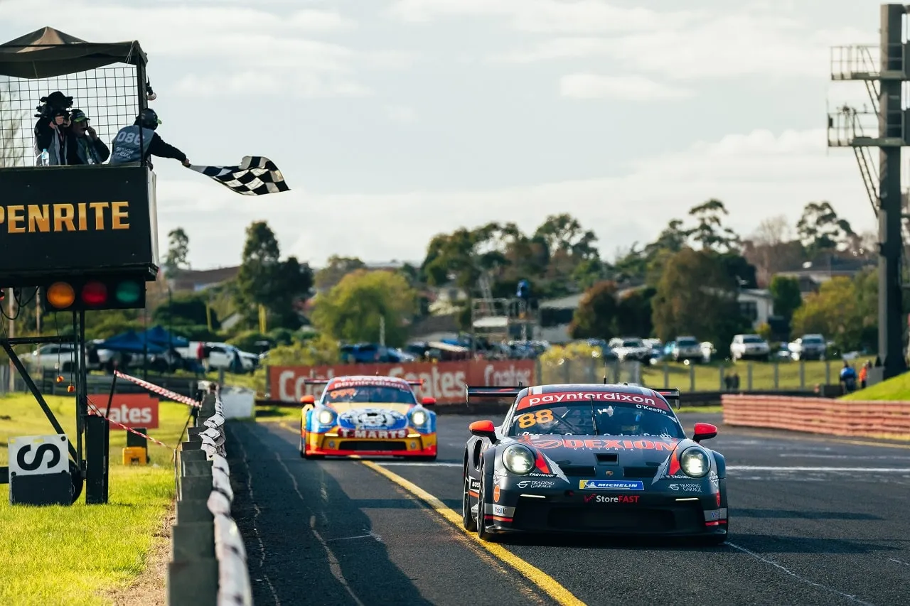 The #88 Dexion Porsche GT3 Cup car takes the chequered flag from a flag marshal, with another Porsche behind