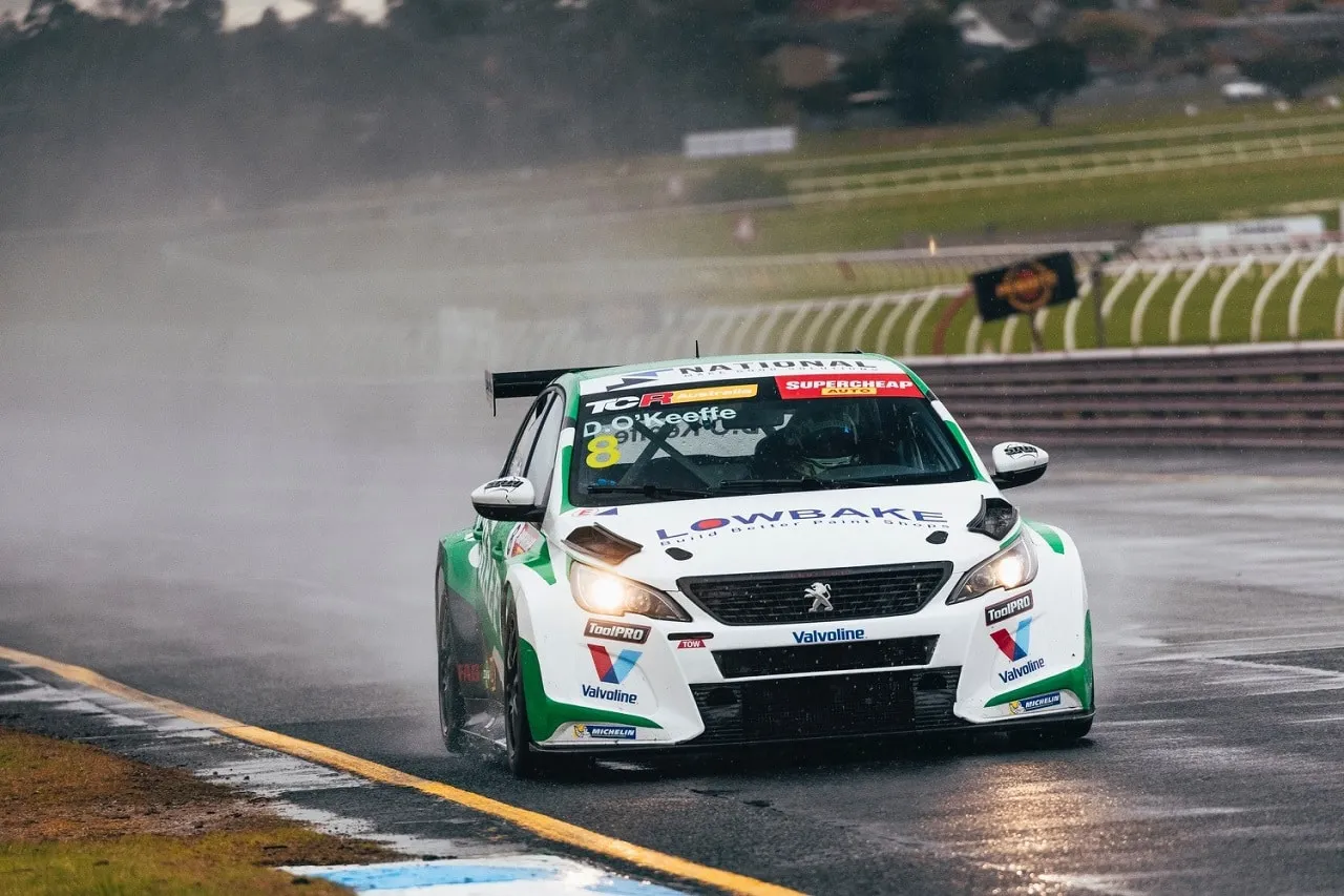 The #8 Schaeffler Peugeot 308 TCR car driving through rain and spray with its headlights on