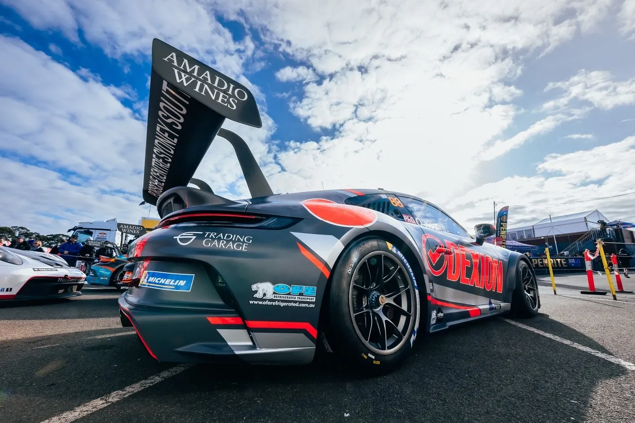 Rear three-quarter view of the #88 Dexion Porsche GT3 Cup car in the paddock under a blue sky
