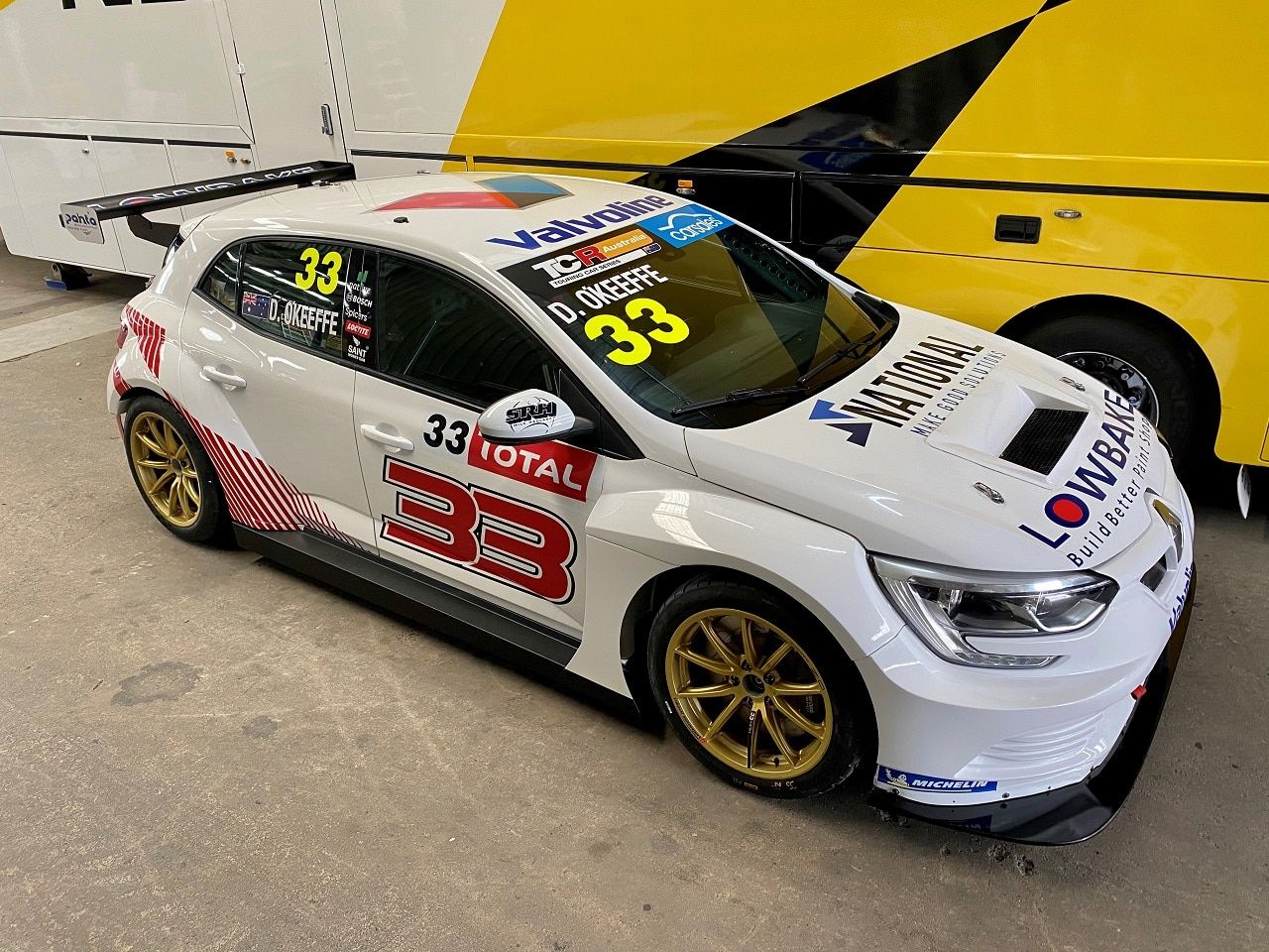 White #33 Renault Megane RS TCR car with red highlights and gold wheels, D. O’Keeffe on the windscreen, in a garage