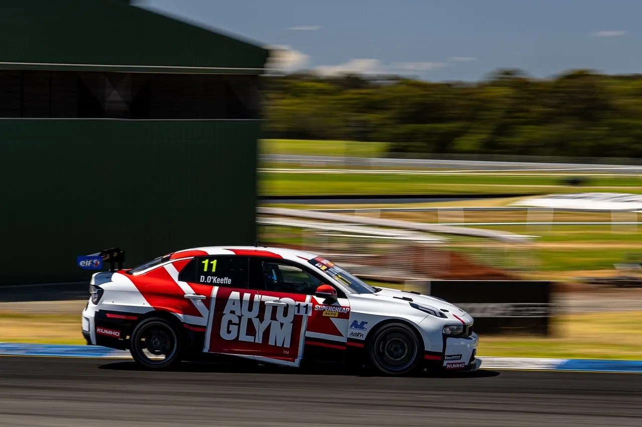 The number 11 Autoglym Lynk & Co TCR car speeding past a green building on track at Sandown