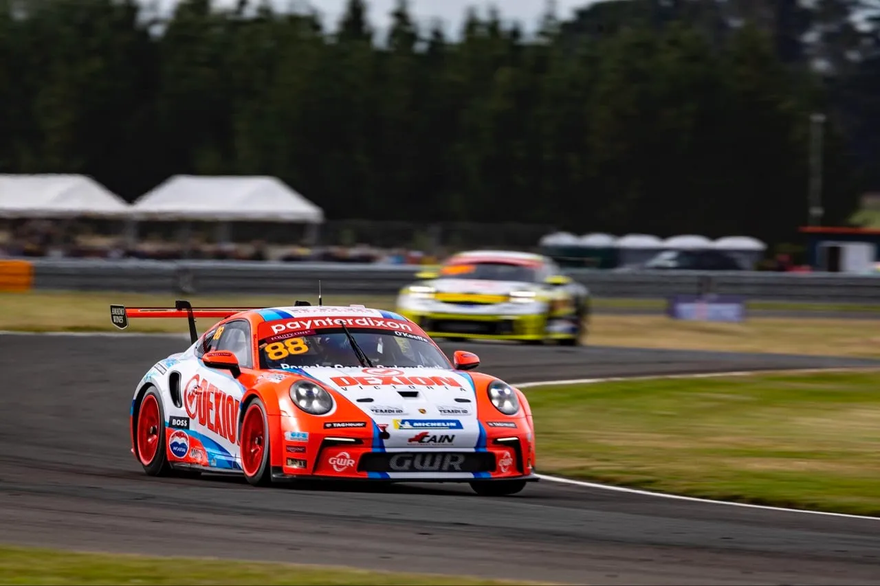 Number 88 Dexion Porsche Carrera Cup car on track with a rival car behind and trees in the background