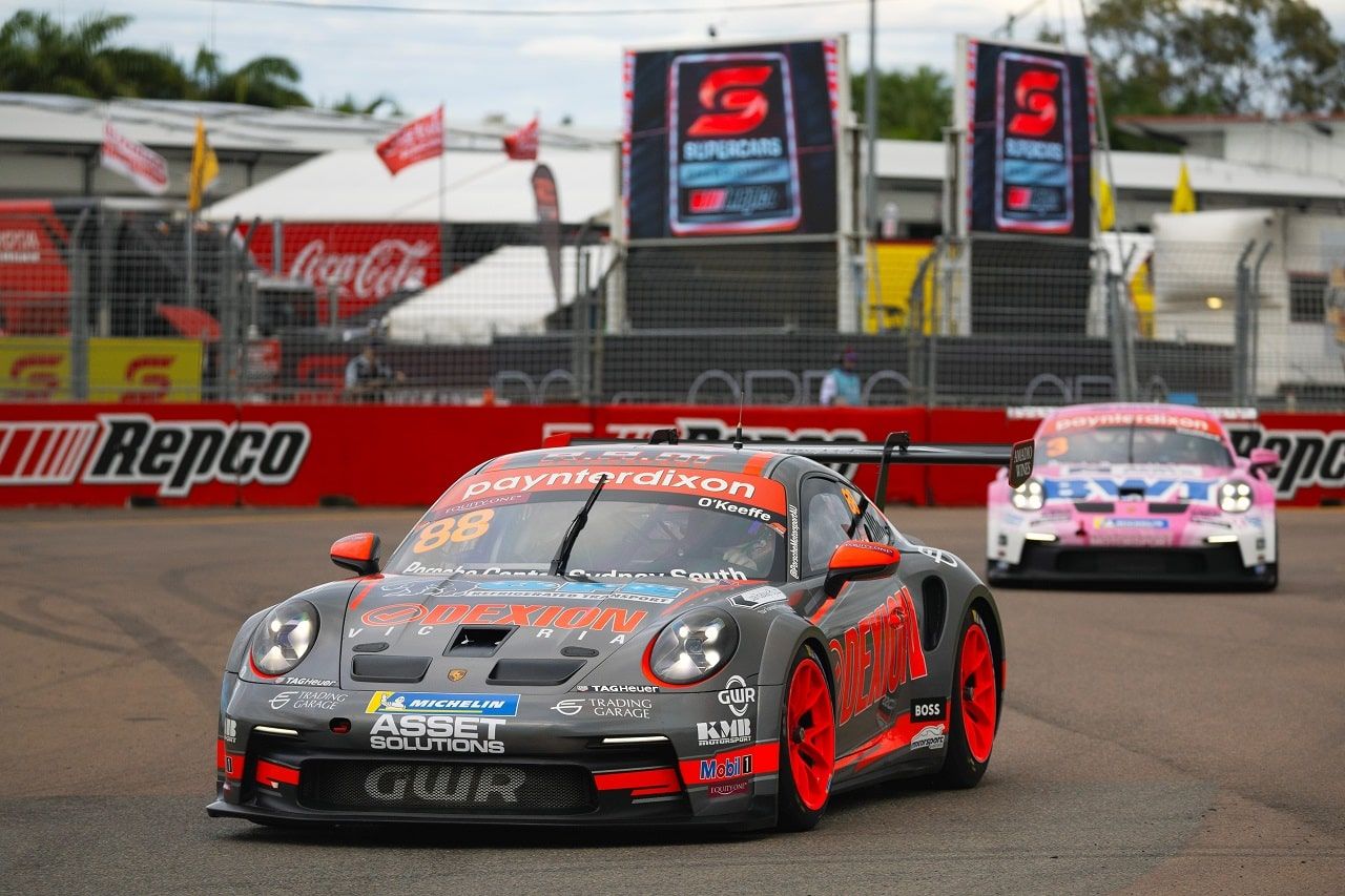The number 88 Dexion Porsche 911 GT3 Cup car on track at Townsville with a pink Porsche behind and Supercars banners