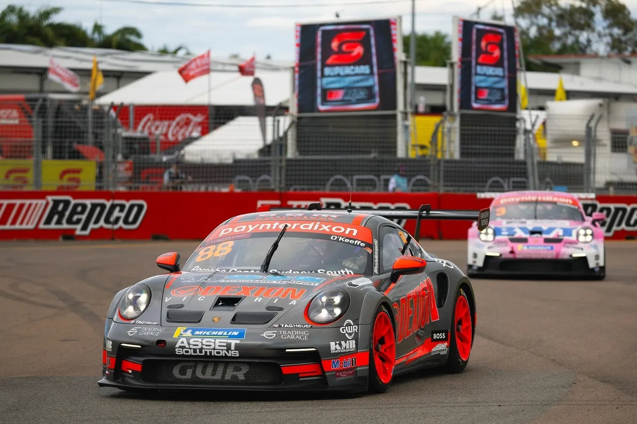 The number 88 Dexion Porsche 911 GT3 Cup car on track at Townsville with a pink Porsche behind and Supercars banners