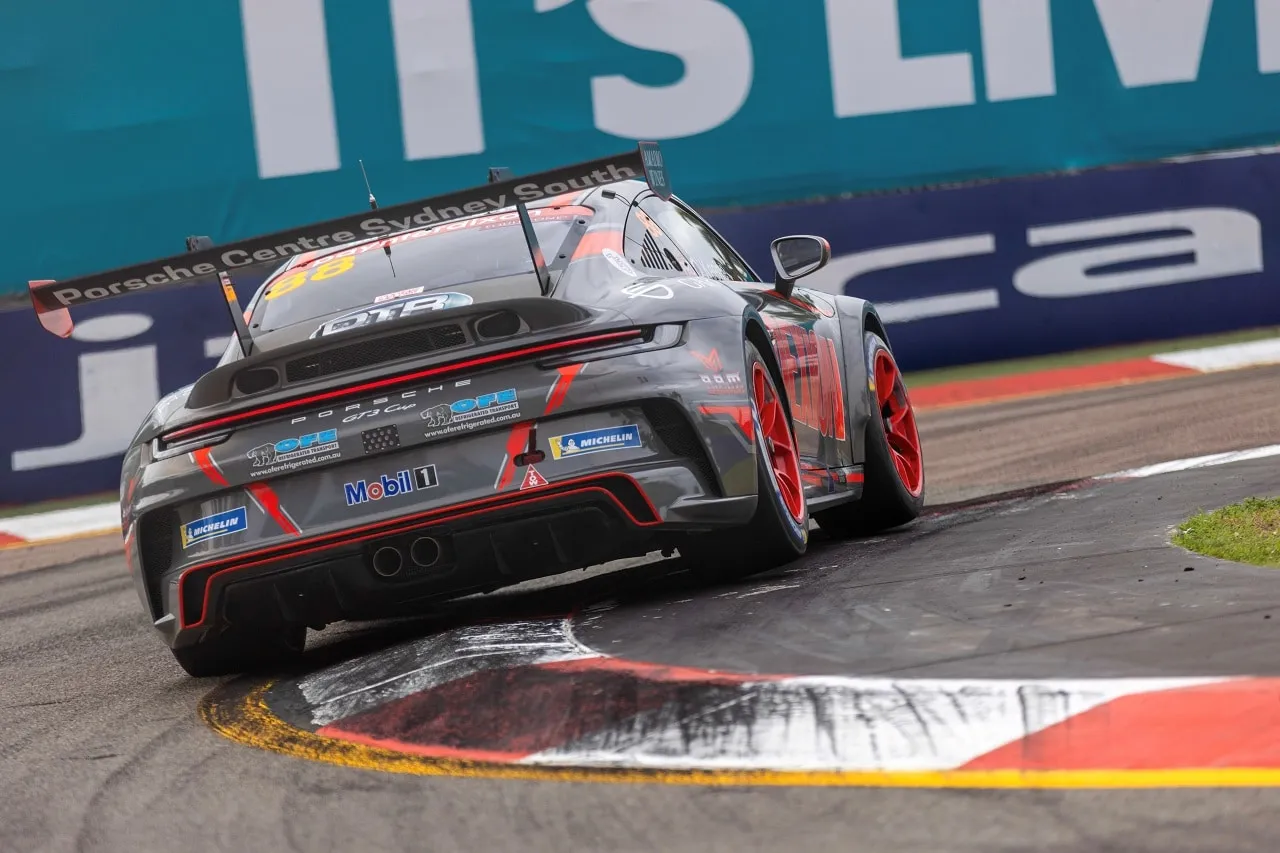 Rear view of the grey Porsche 911 GT3 Cup car cornering over a kerb at Townsville