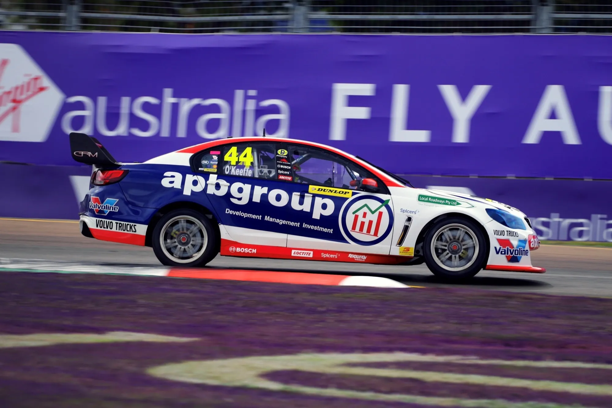 Side view of the #44 apbgroup Commodore Supercar racing past a purple Virgin Australia barrier