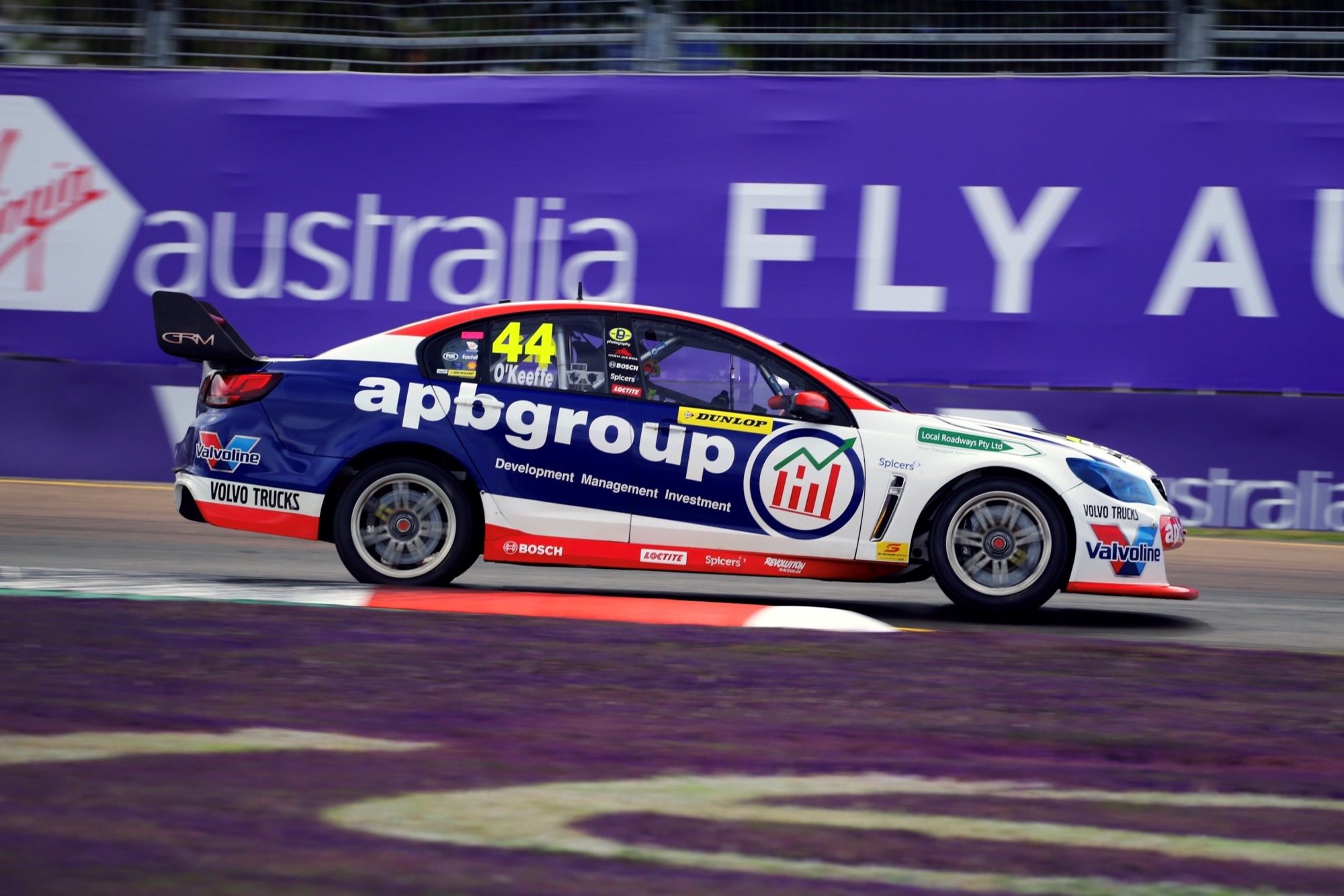 Side view of the #44 apbgroup Commodore Supercar racing past a purple Virgin Australia barrier