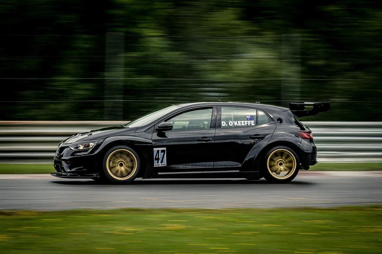 The black Renault Megane TCR car with gold wheels and D. O’Keeffe on the window, seen side on at speed