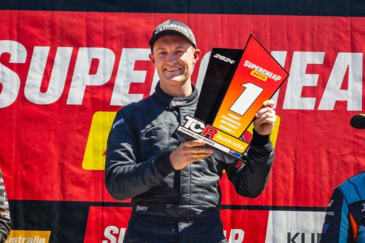 Dylan O’Keeffe smiling on the podium holding a Supercheap Auto TCR Australia winner’s trophy