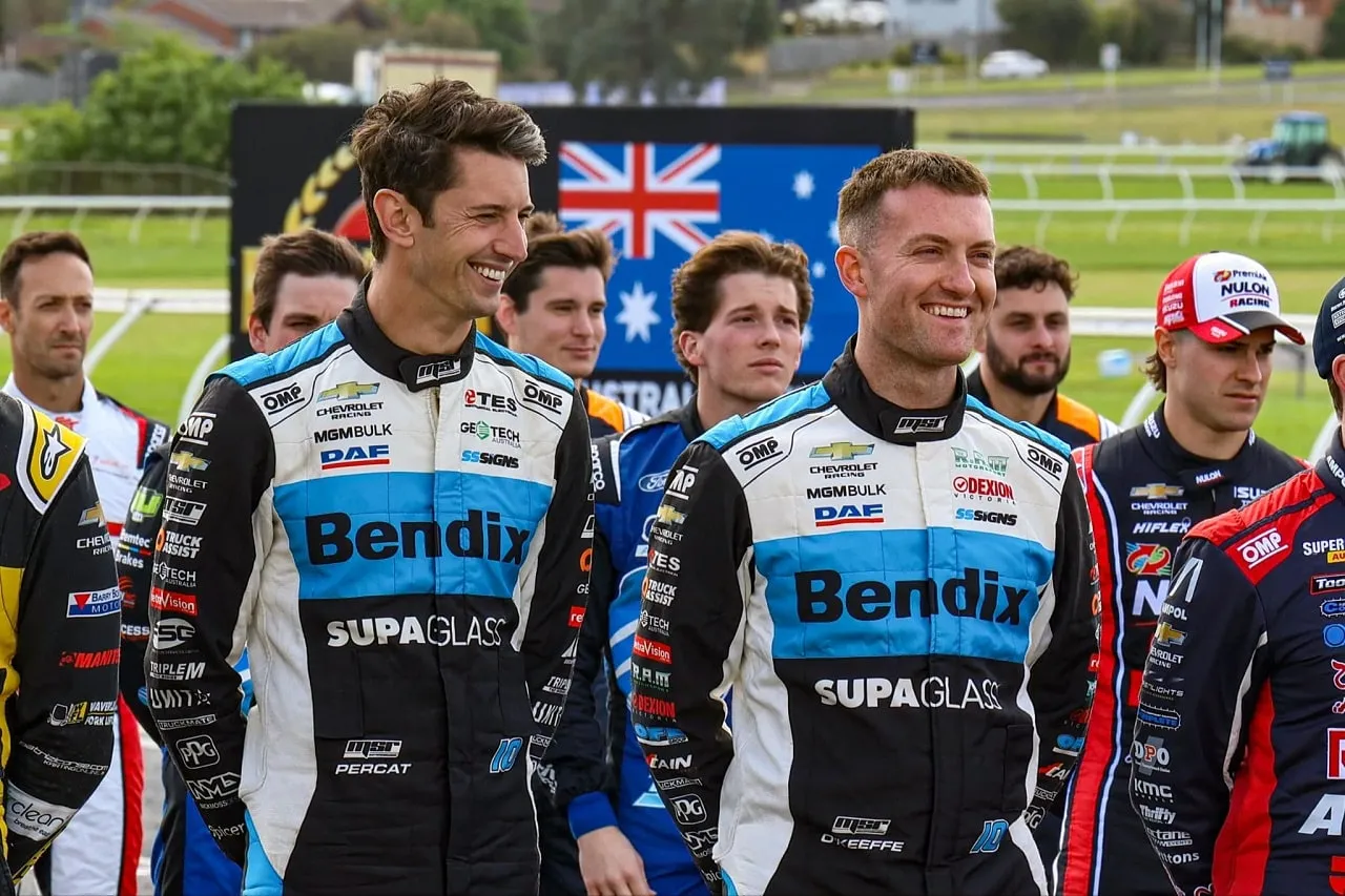 Nick Percat and Dylan O’Keeffe smiling in Bendix Supagas race suits, with other drivers behind them
