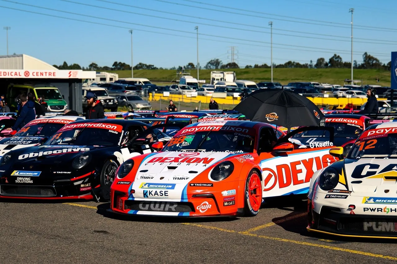 Dexion-liveried Porsche Carrera Cup car among other race cars parked on a paddock grid