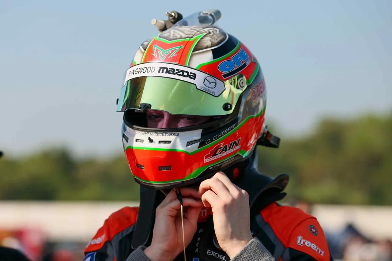 Dylan O’Keeffe in his race helmet adjusting the chin strap outdoors