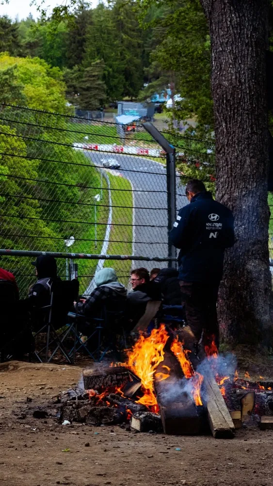 Spectators around a campfire beside the fence at the Nürburgring Nordschleife